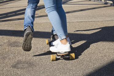 Beine eines jungen Paares beim Fahren auf einem Skateboard - MEMF000943