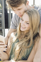 Junges Paar schaut gemeinsam auf ein Smartphone - MEMF000939