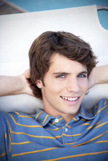 Portrait of smiling young man at the poolside - TOYF001059