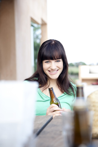 Glückliche junge Frau trinkt ein Bier, lizenzfreies Stockfoto