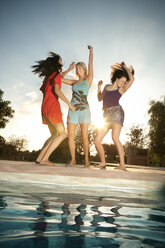 Drei ausgelassene junge Frauen feiern eine Party am Pool - TOYF001079