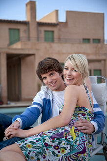 Happy couple on deckchair at the poolside - TOYF001098