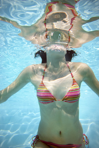 Körper einer jungen Frau unter Wasser in einem Schwimmbecken, lizenzfreies Stockfoto