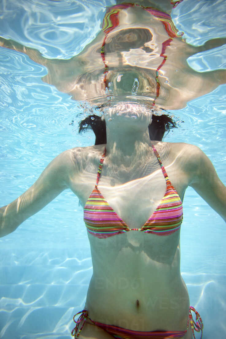 Young woman swimming underwater in pool in underwear Stock Photo