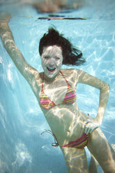 Portrait of laughing young woman underwater in a swimming pool - TOYF001101