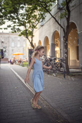 Germany, Berlin, little girl wearing ligh blue summer dress watching soap bubbles - OPF000070