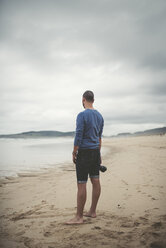 Spanien, Ferrol, Mann mit Kamera am Strand stehend - RAEF000335