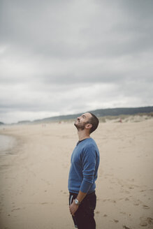 Spanien, Ferrol, Mann steht am Strand und schaut nach oben - RAEF000336