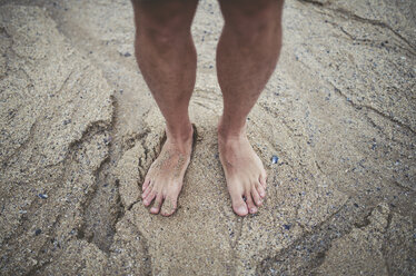 Man's bare feet in the sand on the beach - RAEF000338