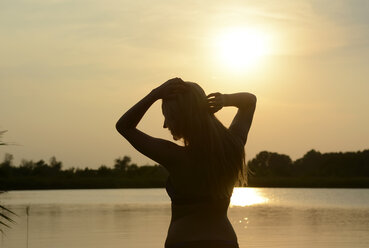 Deutschland, Brandenburg, Silhouette einer jungen Frau vor einem See bei Gegenlicht - BFRF001453