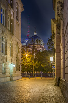 Deutschland, Berlin, Berliner Dom und Fernsehturm durch eine enge Straße bei Nacht gesehen - NKF000355