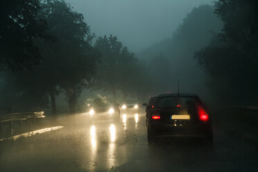 Traffic on county road at rainstorm by twilight - TCF004837