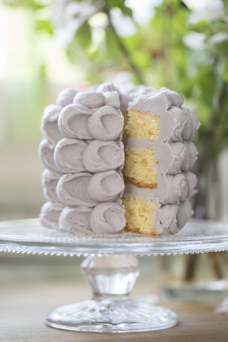 Aufgeschnittene Torte mit lila Baisers auf Tortenständer, lizenzfreies Stockfoto