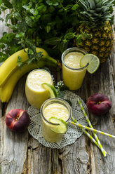 Smoothies of bananas, pineapple and mint on a wooden table - ODF001218