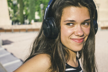 Porträt eines lächelnden Teenagers, der mit Kopfhörern Musik hört - ABZF000103