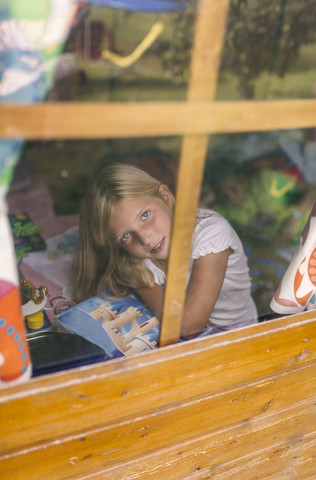 Spanien, Asturien, Gijon, Porträt eines kleinen Mädchens durch ein Glasfenster, lizenzfreies Stockfoto