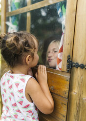 Spain, Asturias, Gijon, Little girls playing through a glass window - MGOF000471