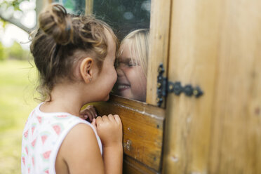 Spain, Asturias, Gijon, Little girls playing through a glass window - MGOF000472