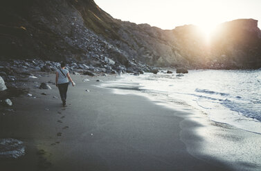 Spain, Ortigueira, woman walking on the sandy beach at twilight - RAEF000345