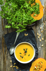 Selfmade pumpkin soup with pumpkin seeds and parsley on a wooden table - ODF001219