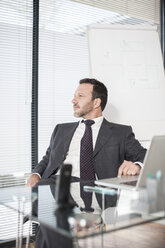 Businessman sitting at desk with laptop - ZEF007393