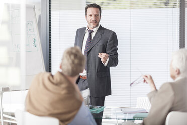 Businessman at flip chart talking to colleagues - ZEF007401