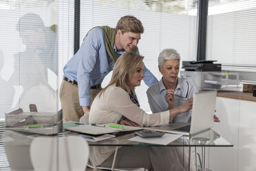 Three colleagues in office working on laptop - ZEF007418