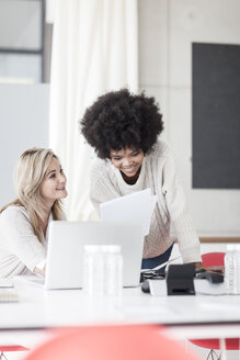 Two colleagues in office working together on laptop - ZEF007433