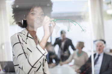 Geschäftsfrau zeichnet auf Glas in einem Besprechungsraum - ZEF007103