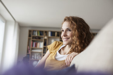 Smiling woman at home sitting on couch - RBF003073