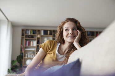 Smiling woman at home sitting on couch - RBF003074