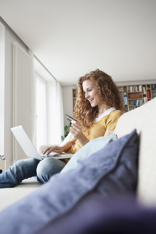 Lächelnde Frau beim Online-Einkauf zu Hause, lizenzfreies Stockfoto