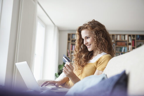 Lächelnde Frau beim Online-Einkauf zu Hause - RBF003082