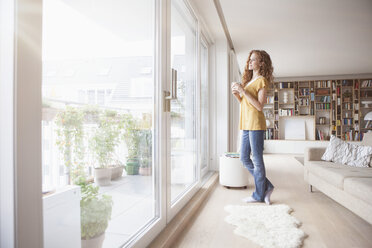 Frau zu Hause schaut aus dem Fenster - RBF003096