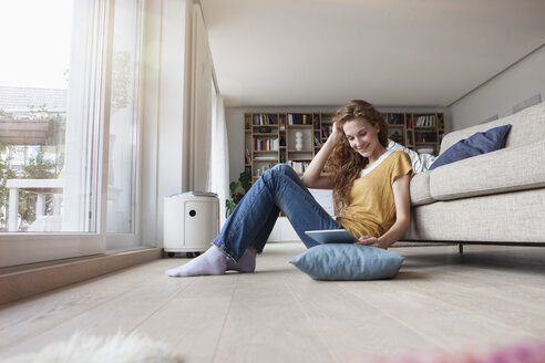 Frau zu Hause auf dem Boden sitzend mit digitalem Tablet - RBF003102