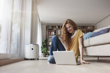 Woman at home sitting on floor using laptop - RBF003103