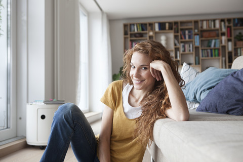 Smiling woman at home sitting on floor stock photo