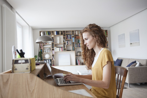 Frau zu Hause mit Laptop auf Sekretärin Schreibtisch, lizenzfreies Stockfoto