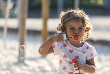 Little girl making soap bubbles at playground - MGOF000478
