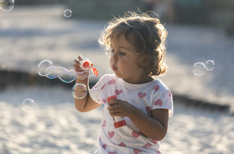 Little girl making soap bubbles at playground stock photo