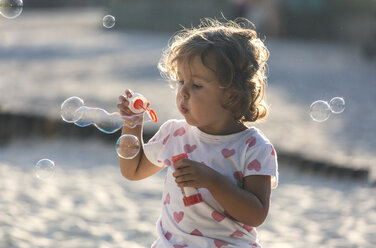 Kleines Mädchen macht Seifenblasen auf dem Spielplatz - MGOF000480