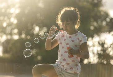 Kleines Mädchen macht Seifenblasen im Park in der Dämmerung - MGOF000481