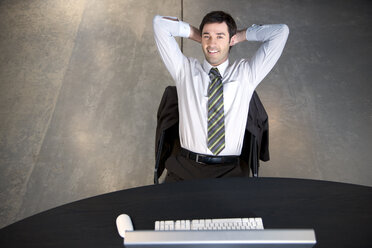 Confident businessman sitting at desk - TOYF001166