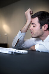 Overworked businessman leaning on desk - TOYF001168