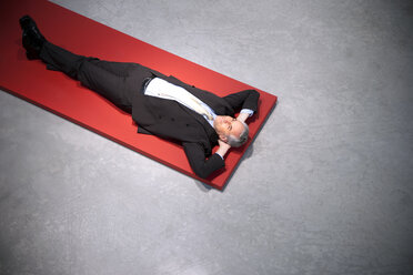 Relaxed businessman lying on floor - TOYF001154