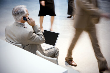 Geschäftsmann mit Mobiltelefon und Laptop mit Passanten - TOYF001237