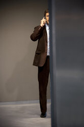 Businessman on the phone behind a wall - TOYF001245