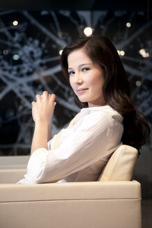 Confident young businesswoman sitting in armchair - TOYF001253