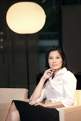 Confident young businesswoman sitting in armchair - TOYF001380