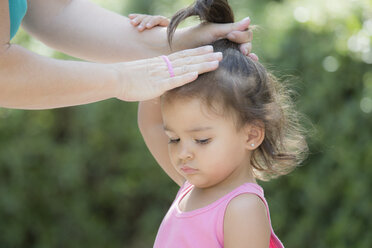 Mutter bindet die Haare ihrer kleinen Tochter - ERLF000025
